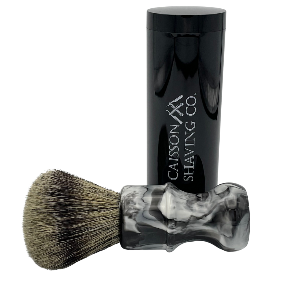 Caisson 24mm synthetic shaving brush lying beside its travel container.