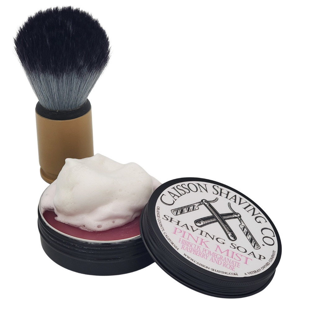 Lathered brush beside an open can of Pink Mist shaving soap.