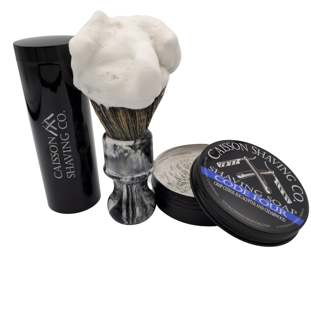 Caisson Code Four shaving soap with a lathered synthetic brush and travel container.