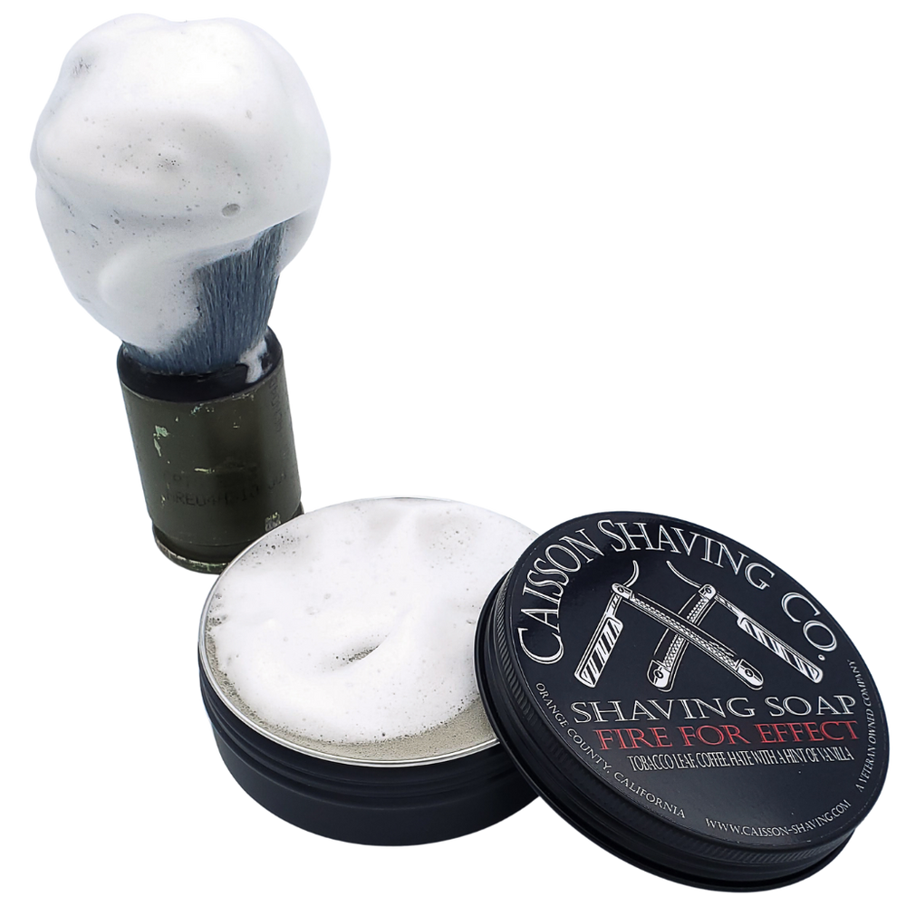 Lathered shaving brush beside an open can of Fire For Effect shaving soap.
